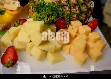 Two types of cheese served on the table, appetizers, decorated with parsley, pineapple, dried figs and strawberries Stock Photo