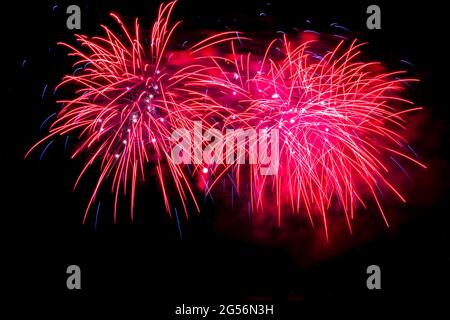 Red fireworks fill the night sky around a full moon Stock Photo