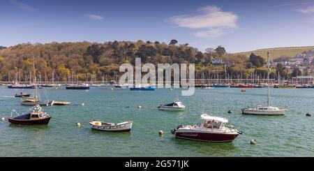 Boats moored on the river Dart at Dartmouth in Devon. In the distance is the 75014 Braveheart steam locomotive arriving at Kingswear. Stock Photo