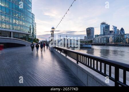 People walking by More London Riverside buildings, modern office buildings with 20 Fenchurch Street or Walkie-Talkie tower in the background at twilig Stock Photo