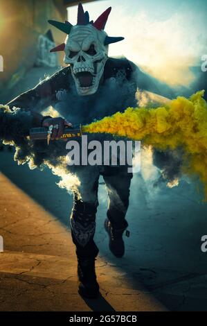 African American male in a demonic skull mask carrying a vibrant yellow smoke bomb Stock Photo