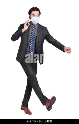 young businessman talking on  mobile phone, walking and wearing a protective medical mask isolated on white background Stock Photo