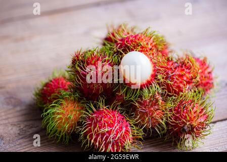 Fresh and ripe rambutan sweet tropical fruit peeled rambutan with leaves, Rambutan fruit on wooden background harvest from the garden Stock Photo