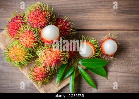 Fresh and ripe rambutan sweet tropical fruit peeled rambutan with leaves, Rambutan fruit on wooden background harvest from the garden Stock Photo