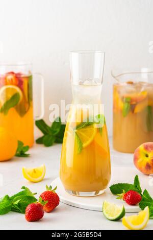 Jugs of fresh refreshing fruit drinks with fruit wedges, summer cold juices with ice Stock Photo
