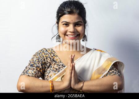 A beautiful Indian woman in saree isolated on white background welcomes in namaste pose with smiling face Stock Photo