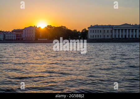 sunset over the houses of a small town on the river bank. sunset in the city on the river. Stock Photo