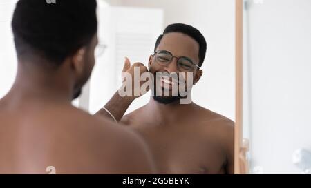 Happy handsome mixed race Black guy in glasses touching stubble Stock Photo