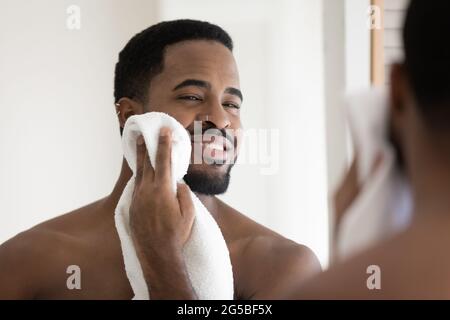 Happy handsome African American guy drying face with white towel Stock Photo