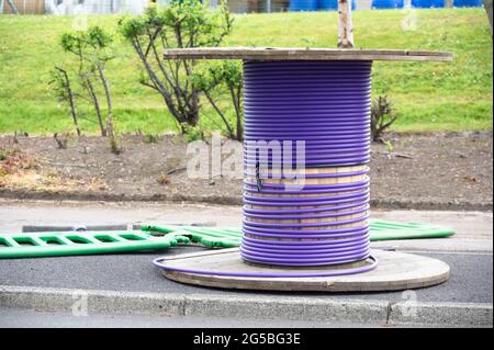 Purple cable and wooden spool with fiber optic cable for fast internet ready to be installed Stock Photo