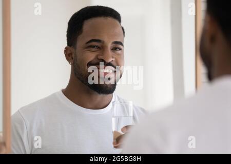 Happy handsome stylish mixed race Black guy drinking pure water Stock Photo