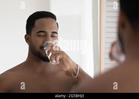 Happy relaxed handsome athletic Black guy drinking pure filtered water Stock Photo