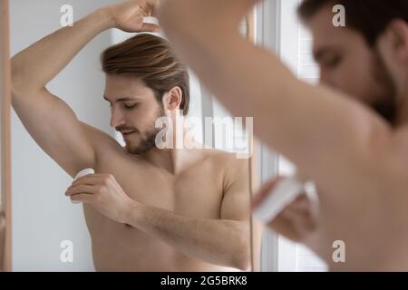 Calm handsome young well built man using deodorant Stock Photo