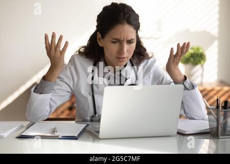 Angry female doctor have problems working on computer Stock Photo