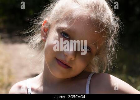 Caucasian blond girl with a cute smile looks sad. Close-up portrait Stock Photo