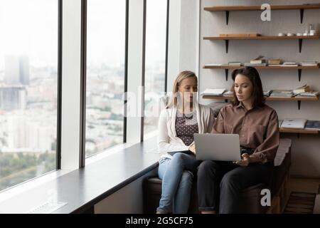 Focused two female colleagues working on computer in modern office. Stock Photo