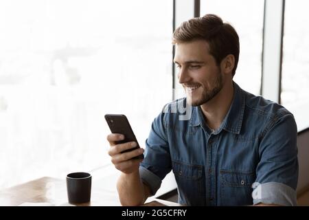 Smiling joyful young man using cellphone. Stock Photo