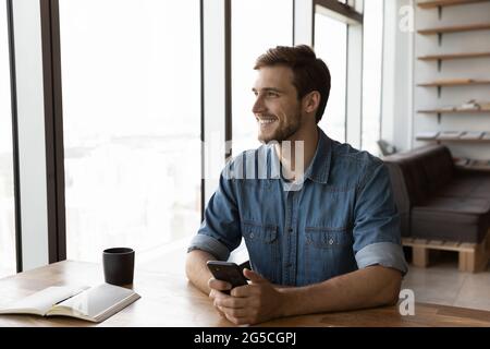Distracted young man holding smartphone in hands. Stock Photo