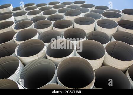 Downpipe warehouse. Steel pipes, parts for the construction of a roof drainage system in a warehouse. Stack of stainless steel pipes. Stock Photo