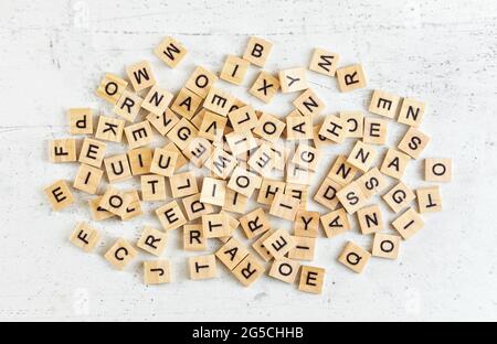 Pile of wooden tiles with various letters scattered on white stone like board, view from above Stock Photo