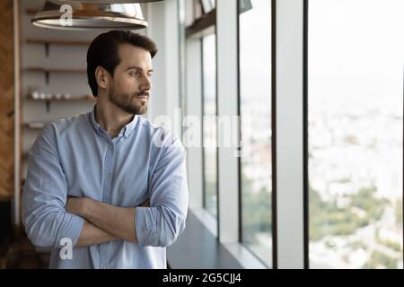 Confident pensive young man looking out of window. Stock Photo