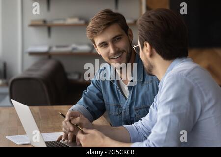 Happy two young male colleagues working on online project. Stock Photo