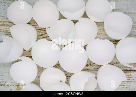 Close up top view of lots of broken white eggshells on an aged wood background. Stock Photo