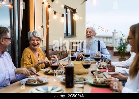 Happy senior friends having fun dining together on house patio - Elderly lifestyle people and food concept Stock Photo