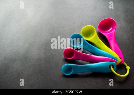 Multi-color empty measuring spoons of different sizes on a black background. Copy space. Stock Photo