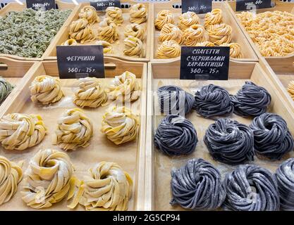 A variety of handmade spaghetti is sold by weight on footcourt. In Russian are written varieties of pasta: fettuccine, pasta Stock Photo