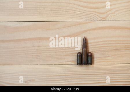 Three different caliber bullets together on a wooden background. Bullets on a wooden background. Military concept. Stock Photo
