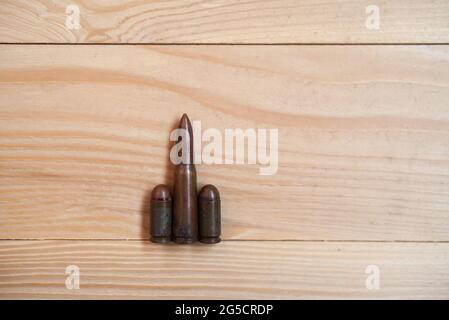 Bullets on a wooden background. Three different caliber bullets together on a wooden background. Military concept. Stock Photo