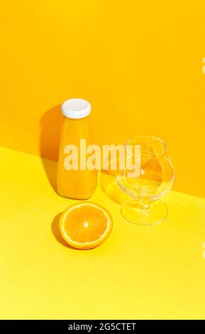 Bottle with orange juice and fresh orange and empty glass on the table. Stock Photo