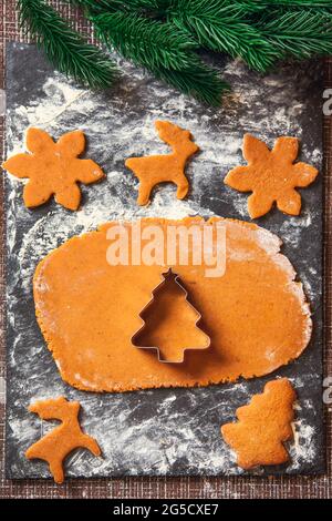 The process of making Christmas Ginger cookies. A Christmas tree-shaped mold on a raw dough for gingerbread cookies. Stock Photo