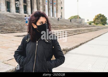 Petrato of a young Latin woman walking down the street with a mask or face mask due to Covid or Coronavirus. Concept coronavirus, personal care, pande Stock Photo