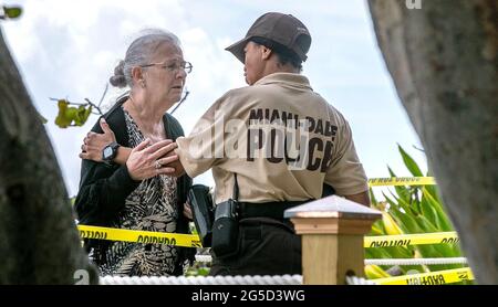 Surfside, USA. 31st Dec, 2000. Miami-Dade Police Officer Barbara Jenkins comforts a woman who is trying to get closer to the site of the Champlain Towers South Condo in Surfside, where her daughter is reported missing after the building collapsed early Thursday morning, as the number of people who are unaccounted for increased to 159 on Friday, June 25, 2021. (Photo by Pedro Portal/Miami Herald/TNS/Sipa USA) Credit: Sipa USA/Alamy Live News Stock Photo