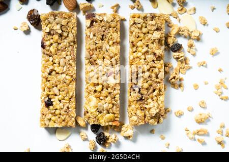 Aerial view of granola or cereal bars with dried fruits and raisins on a white surface. Natural eating concept. Stock Photo