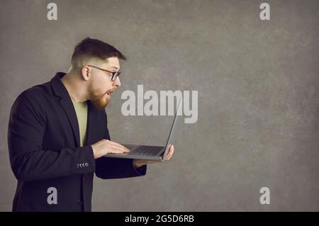 Shocked young man looking at the notification on the screen of his laptop computer Stock Photo
