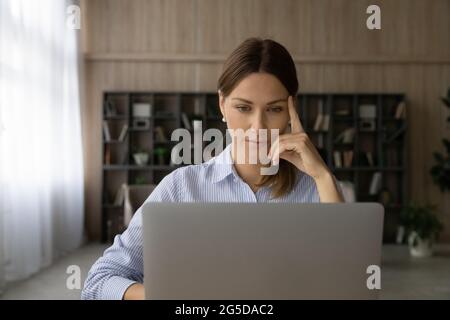 Concentrated thoughtful young business lady working on computer. Stock Photo