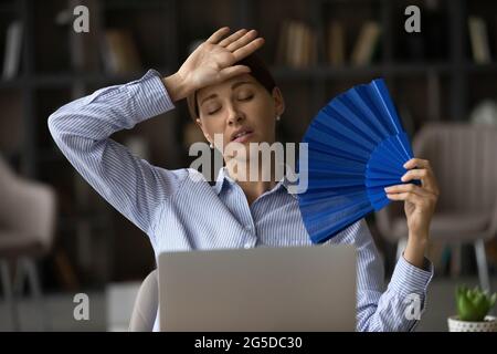 Frustrated unhappy young woman using paper fan. Stock Photo