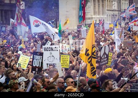 London, UK. 26th June, 2021. Protesters march down Whitehall past Downing Street. Thousands of people marched to raise their concerns regarding government legislation centred around vaccinations and freedom to travel. Credit: Andy Barton/Alamy Live News