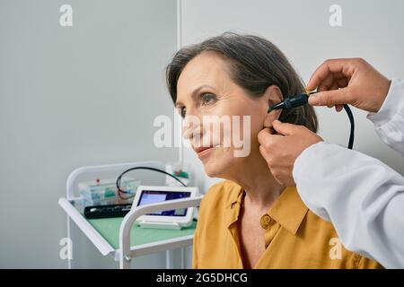 Hearing check-up. Senior citizen woman receives tympanometry with tympanometer probe at hearing clinic. Close-up Stock Photo