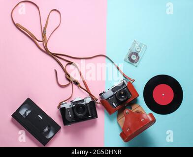 Retro top view still life. Vinyl record, vintage film camera, video and audio cassette on blue pink pastel background. Flat lay. Top view Stock Photo