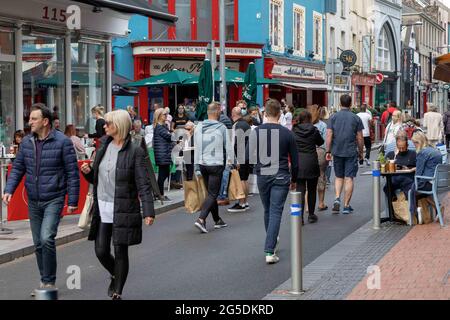 Cork, Ireland. 26th June, 2021. Shoppers Enjoy Warm Weather, Cork, Ireland. Crowds of shoppers descended on Cork City this afternoon to take in the warm weather that is set to continue into late next week. Despite being quite overcast at times the sun broke through soaking the city in the warm sunlight. Credit: Damian Coleman/Alamy Live News Stock Photo