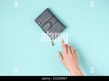 Woman's hand takes a leather wallet on blue background. Top view Stock Photo