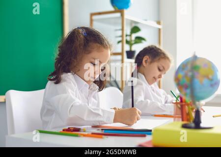 Back to school. Children schoolchildren write while sitting at the table in the classroom. Stock Photo