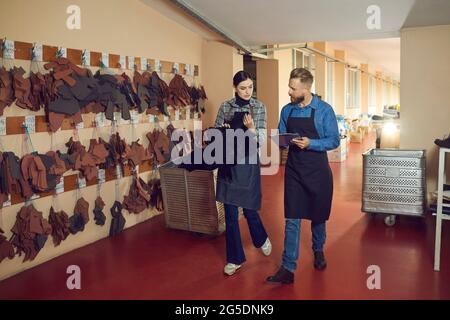 Two employees of a factory that specializes in sewing shoes and clothes discuss new designs. Stock Photo