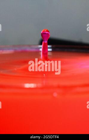 close up of colorful water droplets falling. Waterdrop splash into the water making ripples background. Water droplet closeup. Stock Photo