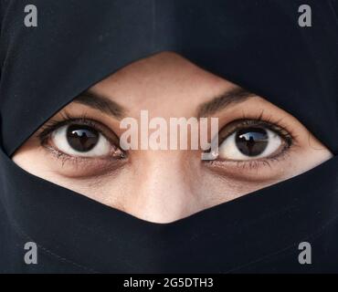 Arab girl with a white veil on her home computer on the sofa in her ...