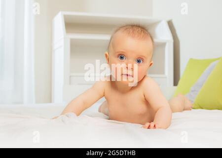 Calm beautiful baby girl standing on hands in bed Stock Photo